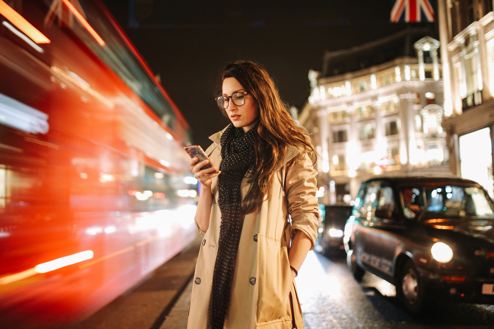 GettyImages-934273752 Portrait of a young woman on the busy streets of London downtown in the evening, texting for a cab