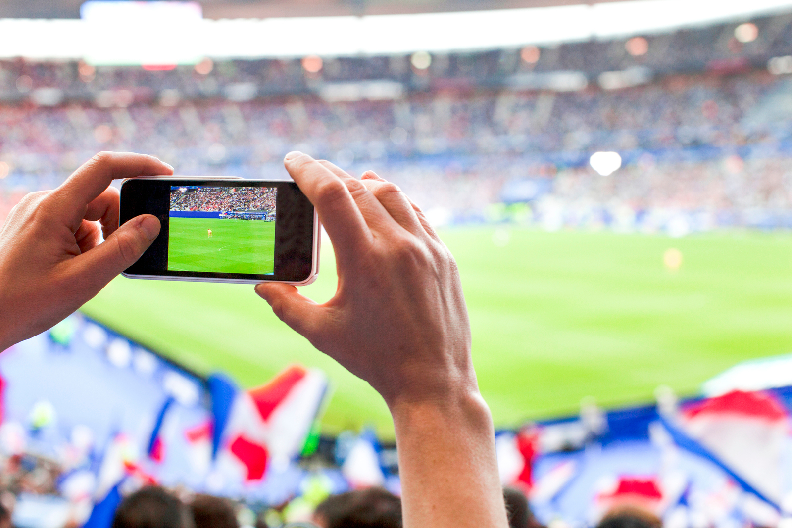 French football fan taking cell phone picture Fan at a soccer game recording the game