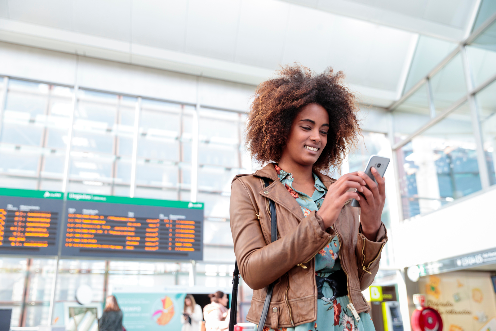 Woman using her mobile phone near train station departures