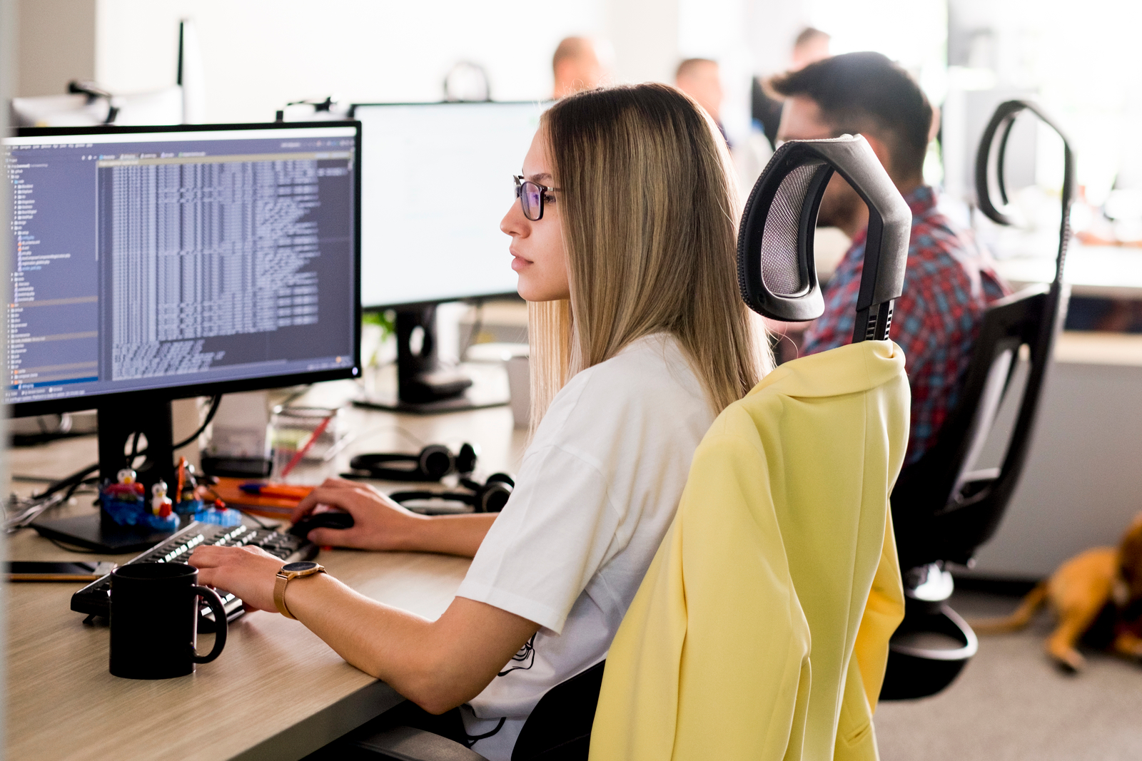 Young female developer sitting at a desk, working on a computer in an IT company